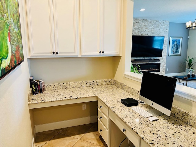 kitchen with light stone counters, white cabinets, light tile patterned flooring, and built in desk