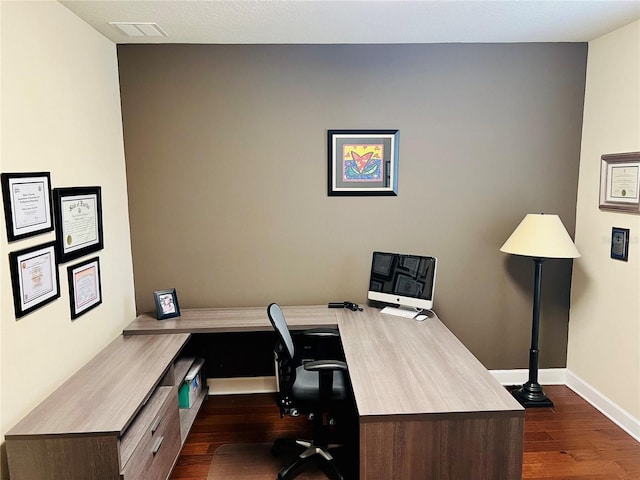 office area featuring dark wood-type flooring, visible vents, and baseboards