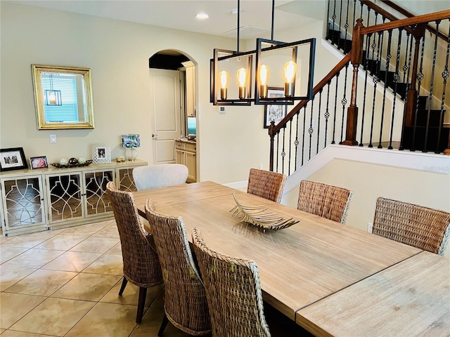 dining area with light tile patterned floors, arched walkways, stairway, an inviting chandelier, and recessed lighting