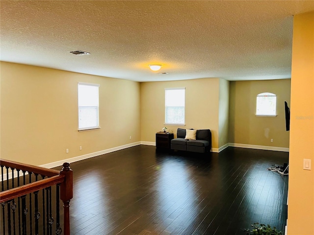 unfurnished room with plenty of natural light, visible vents, and wood finished floors