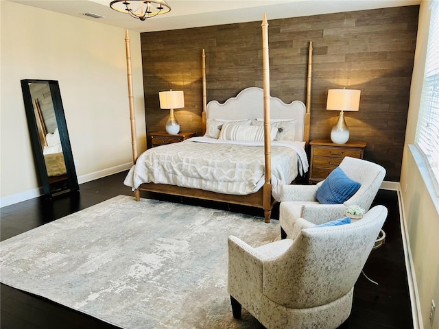 bedroom with visible vents, wood walls, baseboards, and wood finished floors