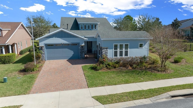 view of front facade featuring a garage, a front lawn, and decorative driveway