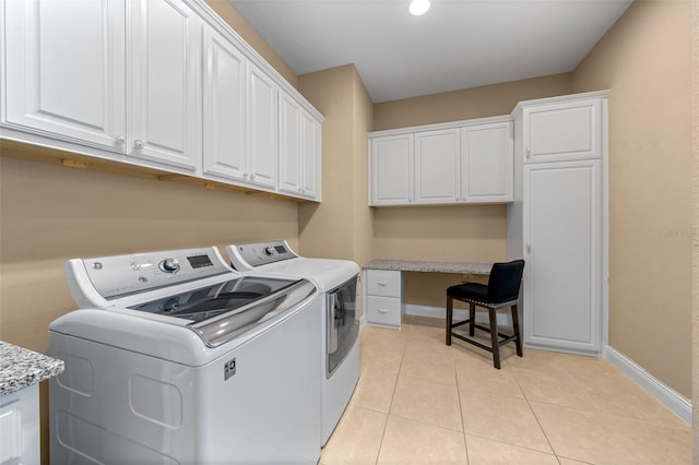 clothes washing area with cabinet space, light tile patterned floors, baseboards, and separate washer and dryer