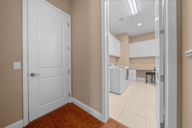 laundry room with cabinet space, independent washer and dryer, baseboards, and light tile patterned floors