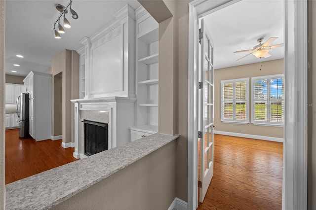 hall featuring dark wood-type flooring, recessed lighting, and baseboards