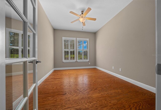 empty room with ceiling fan, baseboards, and wood finished floors