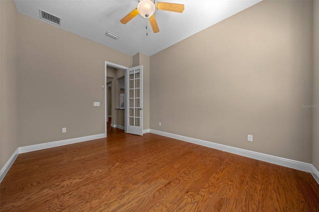 unfurnished room with ceiling fan, wood finished floors, visible vents, and baseboards