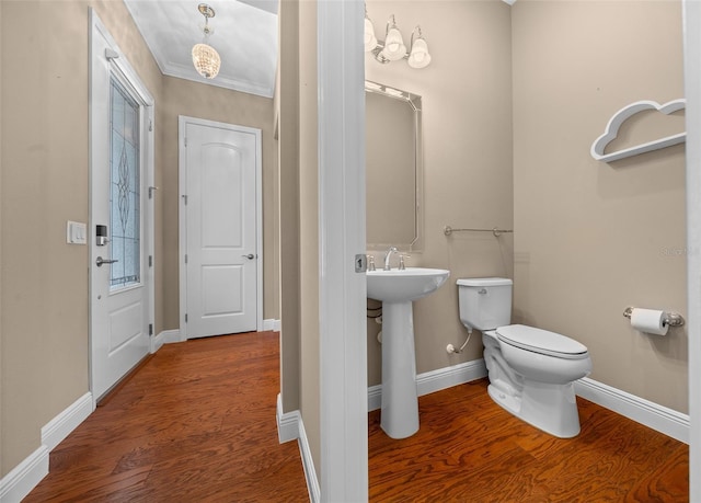 half bathroom featuring a sink, wood finished floors, toilet, and baseboards