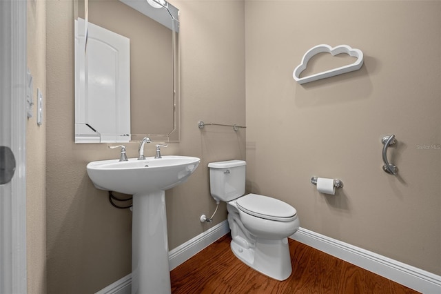 bathroom with baseboards, a sink, toilet, and wood finished floors