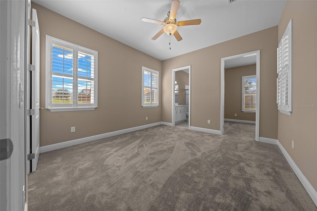 unfurnished bedroom with carpet floors, ceiling fan, ensuite bath, and baseboards