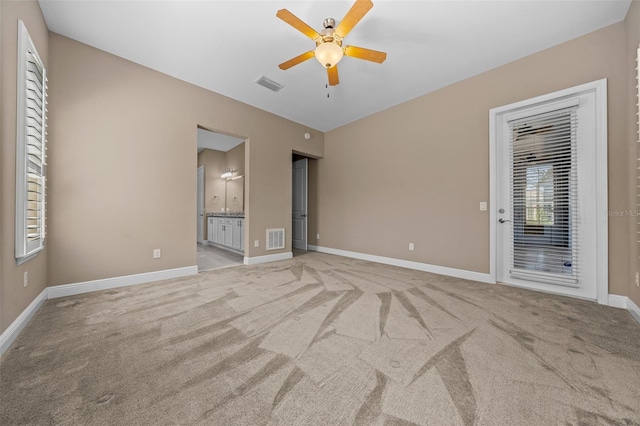 spare room with light carpet, ceiling fan, visible vents, and baseboards