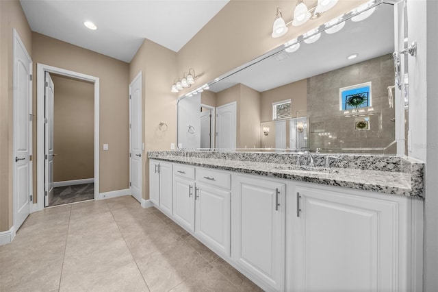 full bath featuring double vanity, baseboards, tile patterned flooring, a walk in shower, and a sink