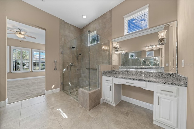 bathroom with ceiling fan, tile patterned flooring, vanity, baseboards, and a stall shower