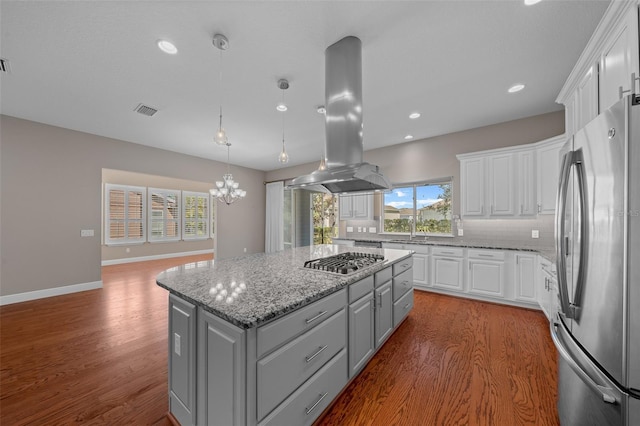 kitchen with gray cabinetry, stainless steel appliances, visible vents, a center island, and island exhaust hood