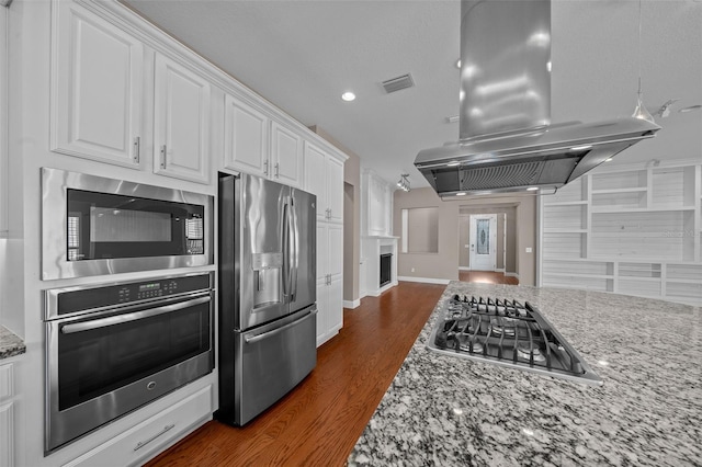 kitchen with stainless steel appliances, island exhaust hood, visible vents, and white cabinets