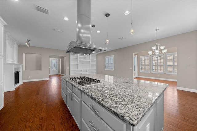 kitchen with a fireplace, island exhaust hood, stainless steel gas stovetop, open floor plan, and a kitchen island