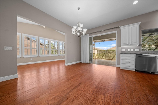 unfurnished dining area featuring a notable chandelier, baseboards, and wood finished floors