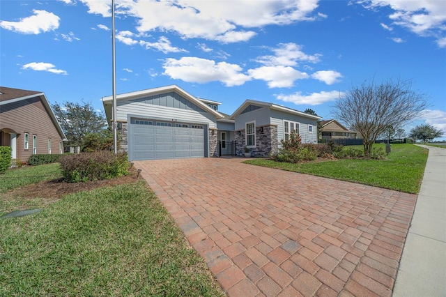 view of front of property with a garage, stone siding, decorative driveway, board and batten siding, and a front yard