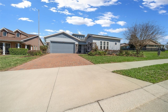 view of front of property featuring stone siding, an attached garage, fence, decorative driveway, and a front yard