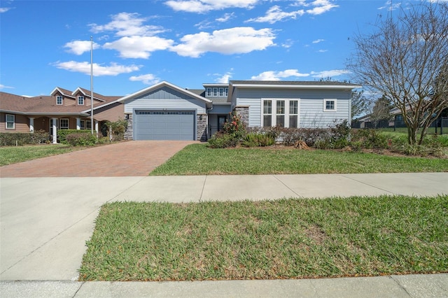 view of front of home featuring a garage, a front yard, decorative driveway, and stone siding