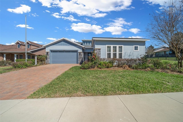 view of front of home with a garage, stone siding, fence, decorative driveway, and a front lawn