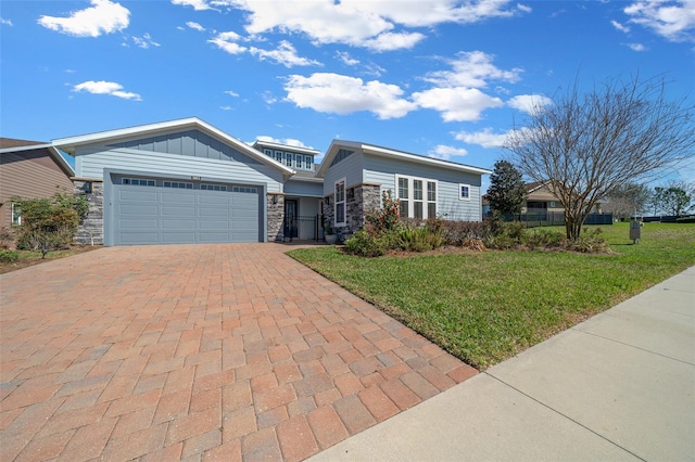 view of front of house featuring a garage, stone siding, decorative driveway, a front lawn, and board and batten siding