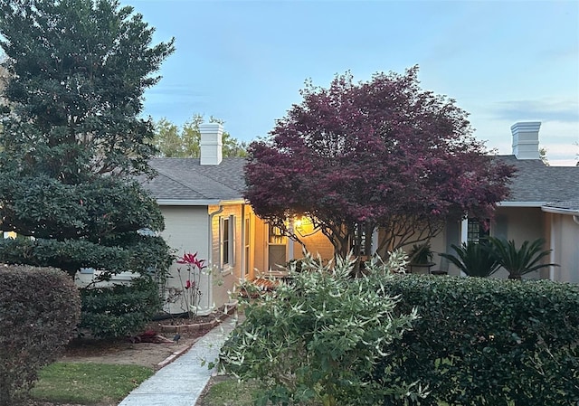 view of side of home featuring a shingled roof and a chimney