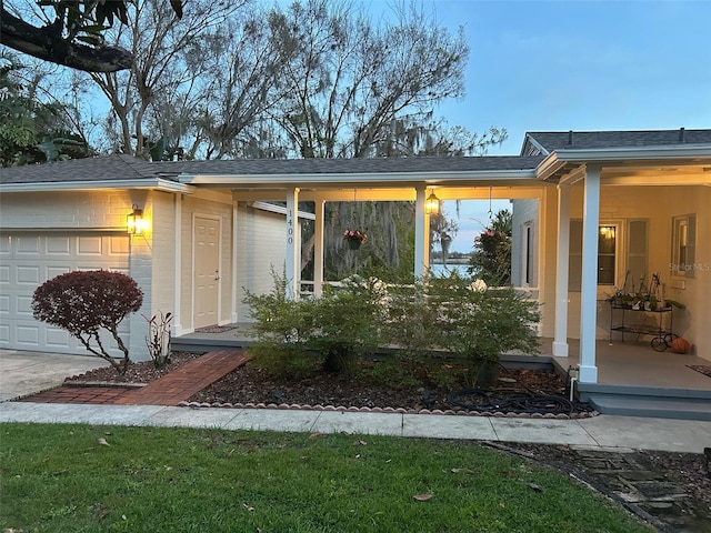 view of exterior entry with a shingled roof and an attached garage