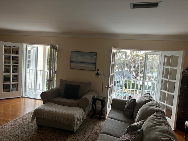 living room with visible vents, crown molding, and wood finished floors