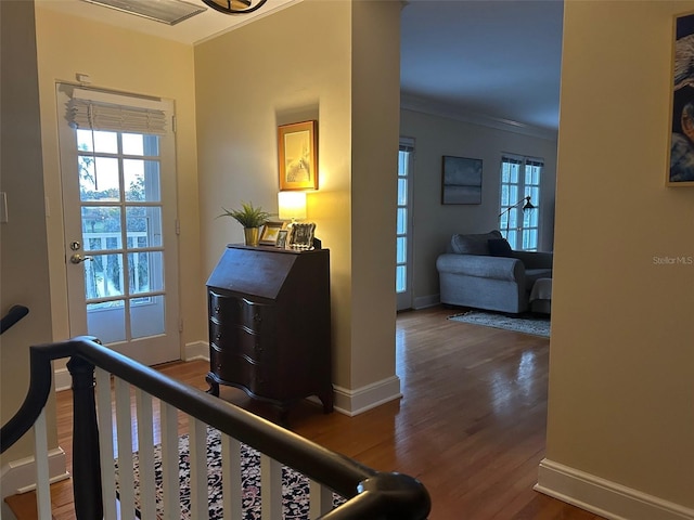 hall featuring dark wood-type flooring, an upstairs landing, crown molding, and baseboards