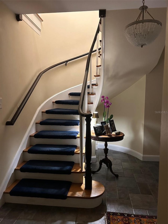 stairway featuring baseboards and stone tile floors