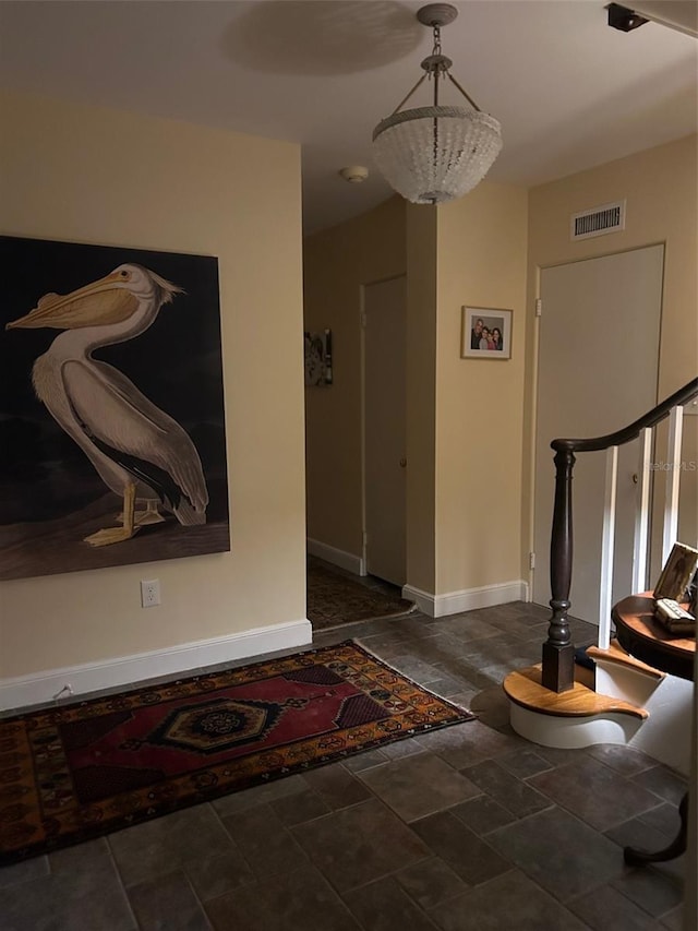 entrance foyer with stairway, baseboards, visible vents, and stone finish flooring