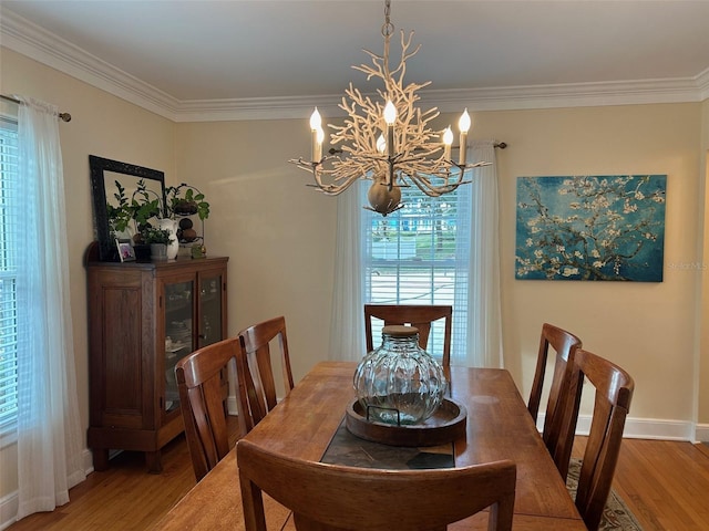 dining space with baseboards, an inviting chandelier, wood finished floors, and crown molding