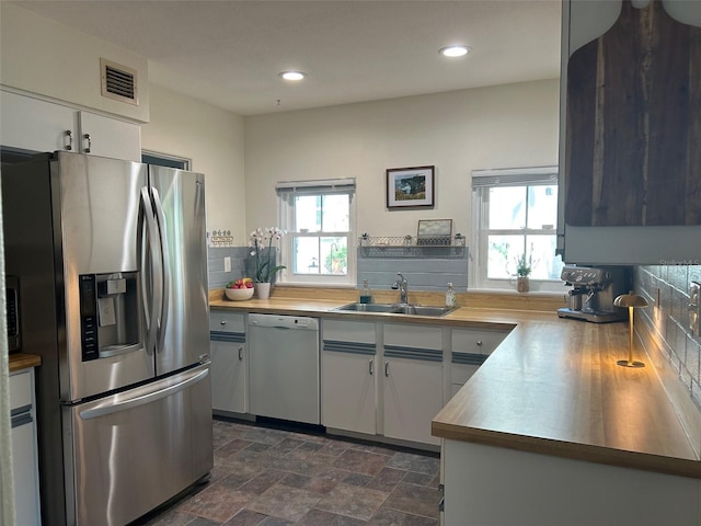 kitchen featuring white dishwasher, a sink, white cabinetry, visible vents, and stainless steel fridge with ice dispenser