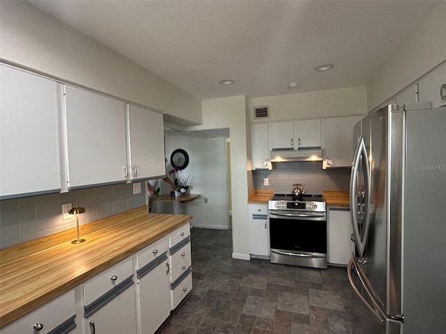 kitchen featuring under cabinet range hood, butcher block countertops, visible vents, white cabinetry, and appliances with stainless steel finishes