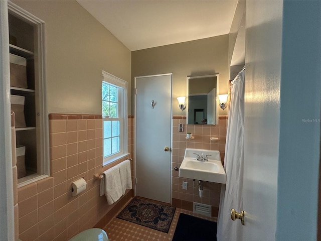 bathroom featuring visible vents, a sink, tile patterned flooring, and tile walls