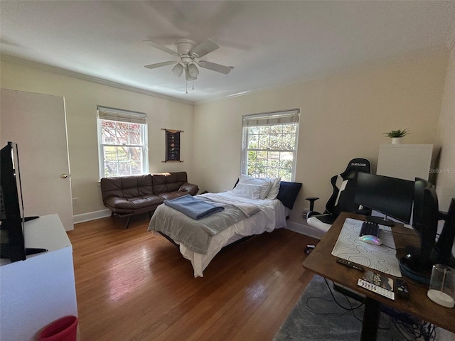 bedroom featuring ornamental molding, wood finished floors, a ceiling fan, and baseboards