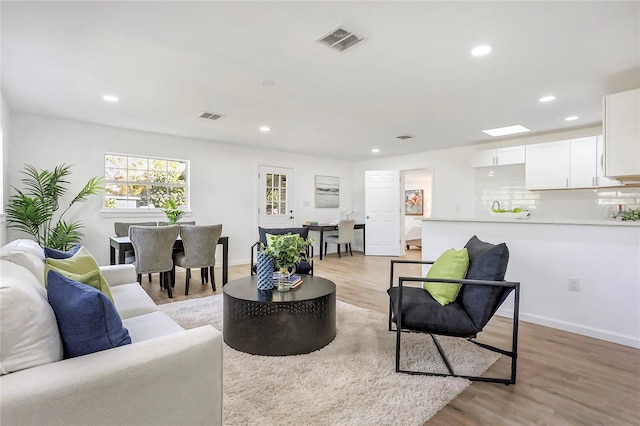 living area featuring light wood-style floors, baseboards, visible vents, and recessed lighting