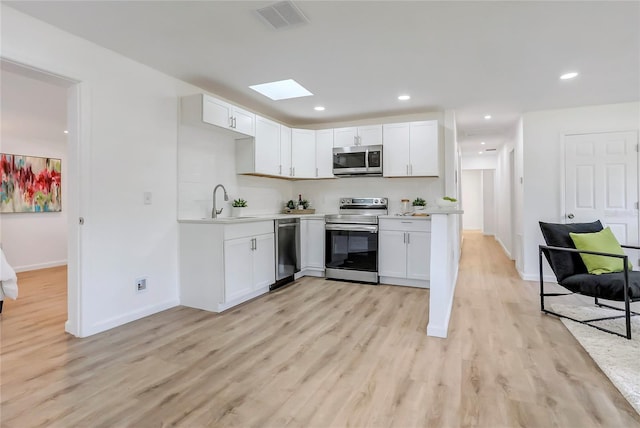 kitchen with light wood-style flooring, visible vents, white cabinetry, light countertops, and appliances with stainless steel finishes