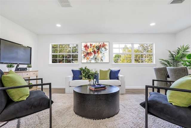 living area featuring a wealth of natural light, wood finished floors, visible vents, and recessed lighting