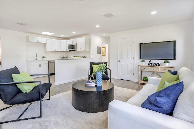 living room with baseboards, light wood-type flooring, visible vents, and recessed lighting