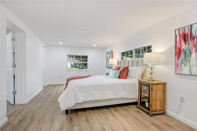 bedroom featuring multiple windows, wood finished floors, and baseboards