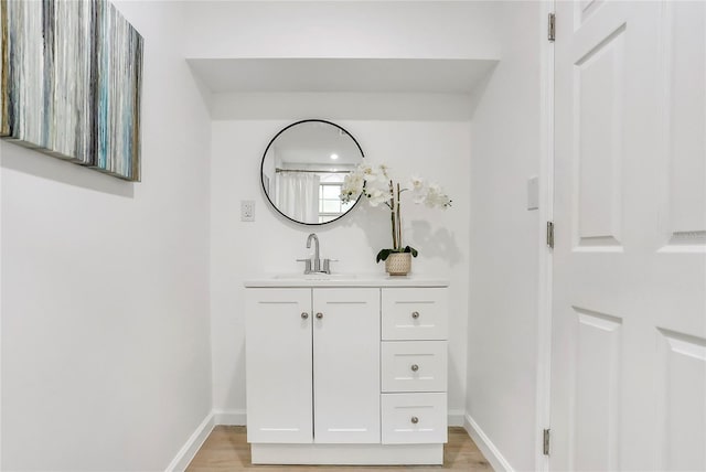 bathroom featuring baseboards, wood finished floors, and vanity