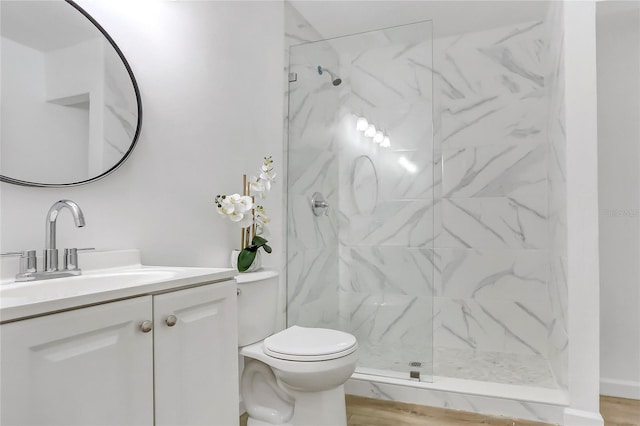 bathroom featuring vanity, a marble finish shower, and toilet