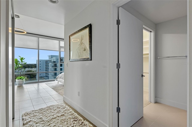 corridor with light tile patterned flooring and baseboards