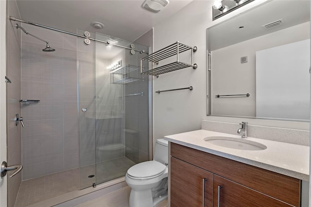 bathroom featuring toilet, vanity, a shower stall, and visible vents