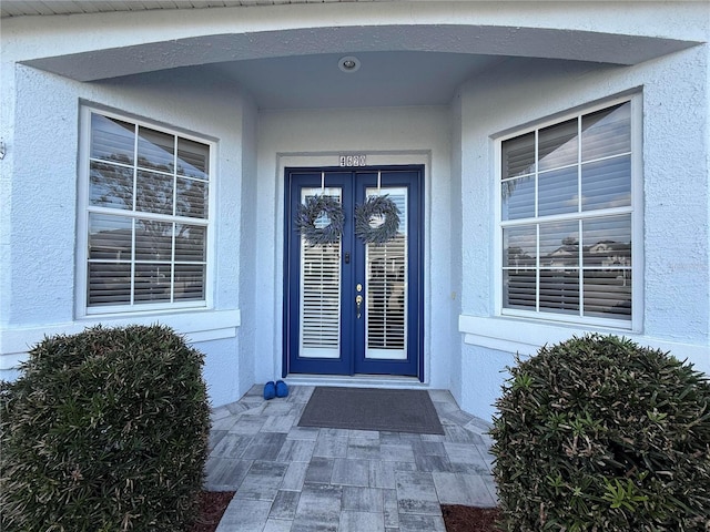 doorway to property featuring french doors and stucco siding