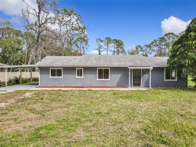 rear view of house featuring an attached carport and a lawn