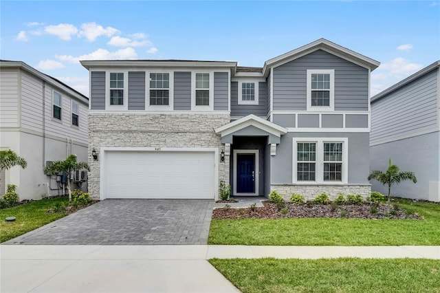 view of front of property with stone siding, a front lawn, decorative driveway, and an attached garage