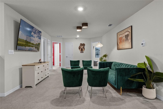 cinema room featuring baseboards, visible vents, a textured ceiling, and light colored carpet